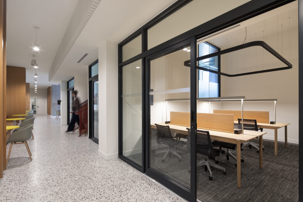 GEOpark hallway with glass meeting room, work tables, and lounge seating along the corridor.