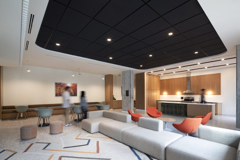 GEOpark resident lounge with sofas, colorful chairs, tables, and a kitchen area.